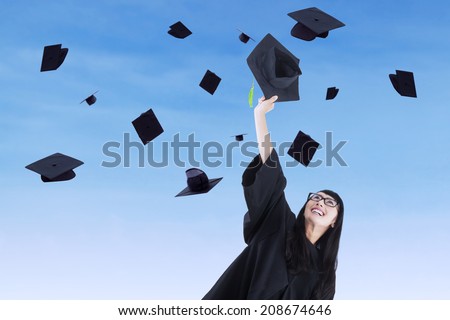 Asian graduate throw graduation cap under blue sky