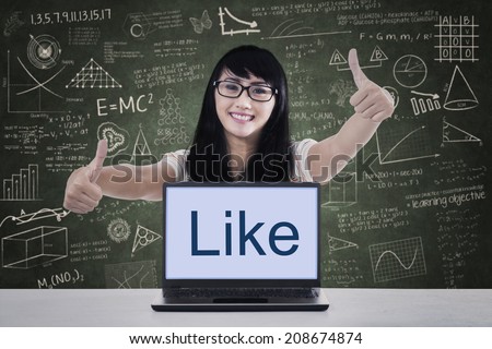Portrait of happy college student giving thumbs up with like on laptop. shot in class