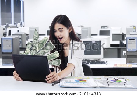 The woman in front of the laptop with fly out dollars