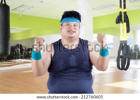 Cheerful fat man in fitness center after workout