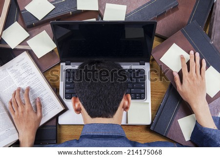 Student sleeping on laptop around books and sticky notes