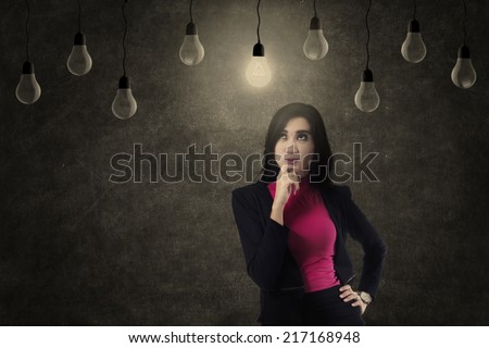 Beautiful businesswoman positive thinking under lit light bulb