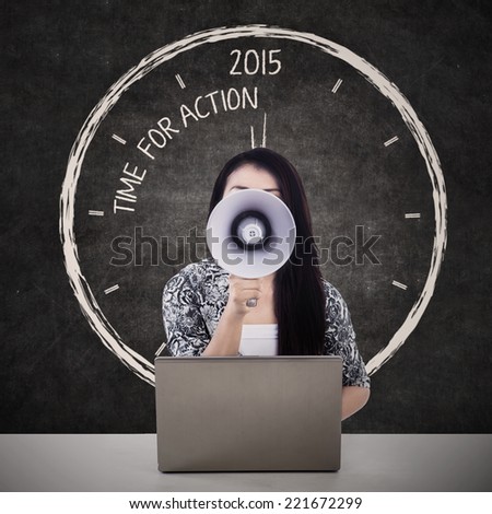 Businesswoman with megaphone and the word time for action in 2015 on the blackboard