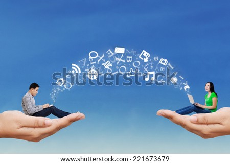 Two asian people sitting on hands and using laptop computer to share information