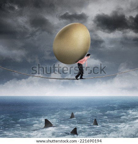 Asian businessman carrying golden egg while walking on the rope above sea
