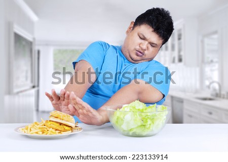 Overweight person refuse to eat fast food and choose vegetable in the kitchen