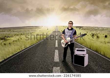 Portrait of talented guitarist playing electric guitar on the road