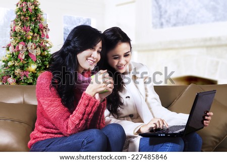 Happy two young women shopping online with laptop at home