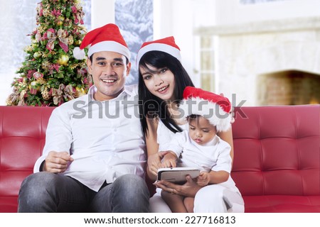 Portrait of hispanic family wearing christmas hat and smiling on camera at home