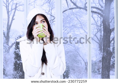 Portrait of girl relaxed at home in winter holiday and enjoy a warm drink while wearing a winter coat