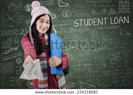 Lovely female student wearing warm clothes in the class and giving money dollars