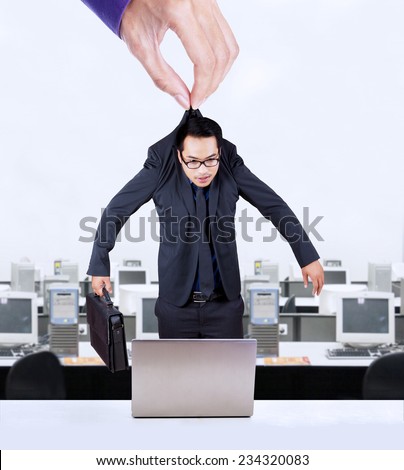 Businessman hanging on a hand and put in an office to work, symbolizing worker exploitation