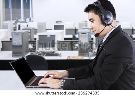 Young businessman working with laptop computer and headphone in the office, symbolizing customer support