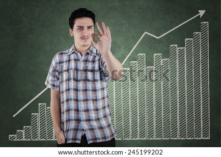 Portrait of caucasian worker in casual clothes showing OK sign with financial chart background