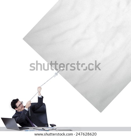 Portrait of businessman in business suit pulling an empty banner with laptop on the table