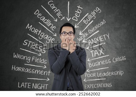 Young business person biting his nail with scared expression, facing many pressure