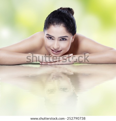 Beautiful model with clean skin and water reflection, lying down while smiling at the camera