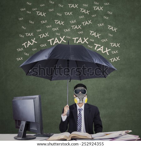 Businessman wearing a gas mask and umbrella to protect him from tax
