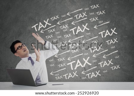 Young businessman working with laptop having tax payment pressure