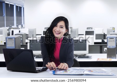 Attractive young asian businesswoman with beautiful face, smiling at the camera in the office