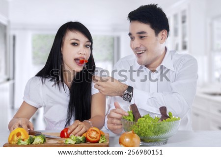 Vegetarian couple cook and eat vegetables salad in the kitchen at home