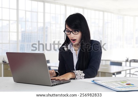 Amazed businesswoman looking at the laptop computer while working in the office