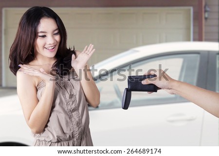 Beautiful teenage girl looks happy and surprised when get a new car and the key