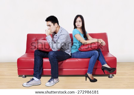 Couple sitting back to back after a fight on the sofa