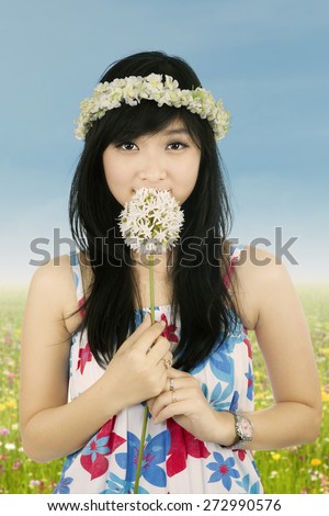 Beautiful woman with crown of flower is smelling flower