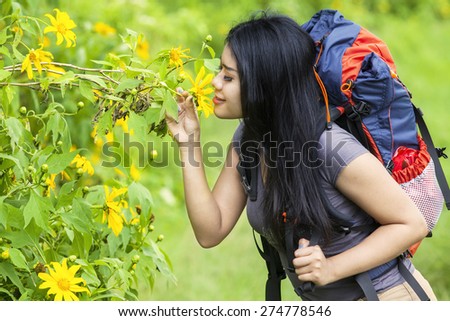 Portrait of happy female hiker kiss a flower while carrying a backpack to hike the mountain