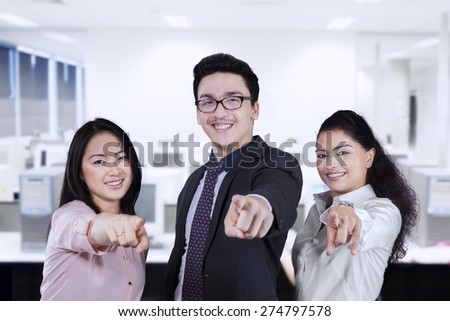 Group of young entrepreneurs smiling and pointing at camera in the workplace