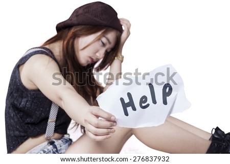 Teenage girl sitting alone and looks sad, showing a paper with a help text
