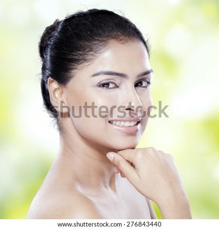 Closeup of attractive girl with fresh skin, pretty face, and black hair, smiling at the camera