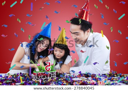 Happy girl celebrate her birthday and cutting birthday cake with her parents