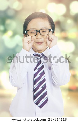 Cute little businessman with formal suit, pretending to cry, shot with bokeh background