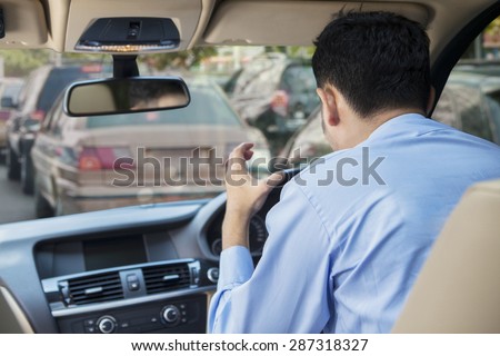 Rear view of furious young man driving a car on the road at the traffic jam