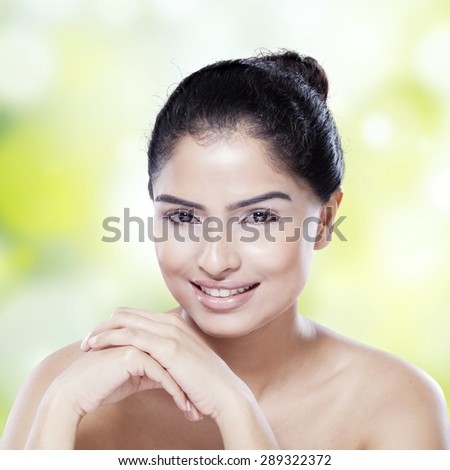 Closeup of attractive girl with beautiful face and natural skin, smiling at the camera on blur background
