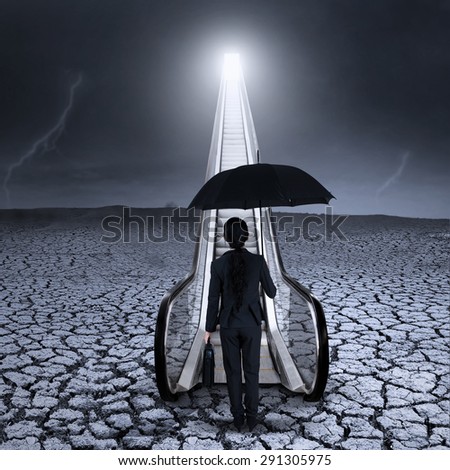 Young businesswoman standing by the escalator on dried land with bad weather