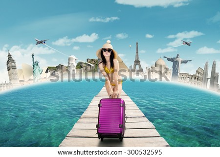 Pretty woman carrying luggage and wearing bikini on the bridge to enjoy the journey to the worldwide monument