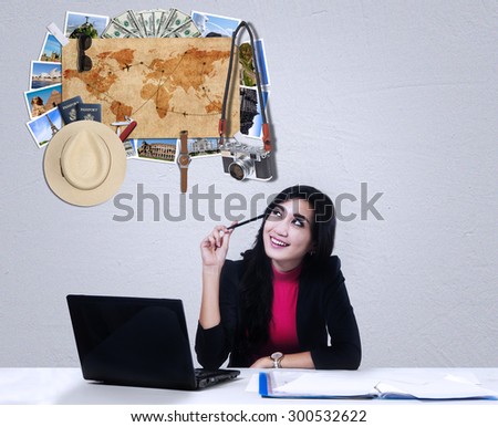 Young businesswoman working with laptop while dreaming a vacation to the famous place around the world