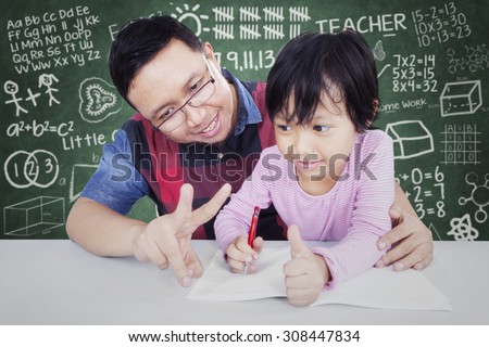 Portrait of young male teacher teach his female elementary school student to calculate with her finger in the classroom