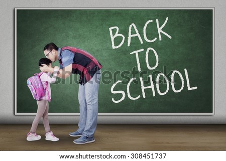 Concept of back to school with a young father kiss his daughter in the classroom before studying