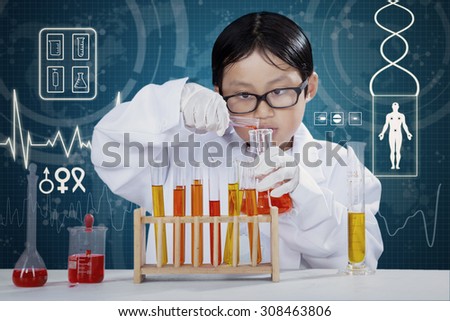 Portrait of little boy wearing coat and make experiments in the laboratory with chemical fluid