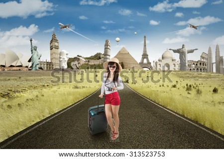 Female tourist standing on the road while carrying luggage with famous landmarks on the back