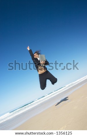 Businesswoman wearing a sunglasses and holding a laptop jumping around