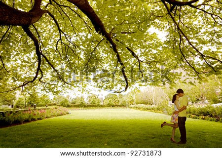 Asian young couple kissing under tree near St. Patrick Cathedral, Melbourne - Australia