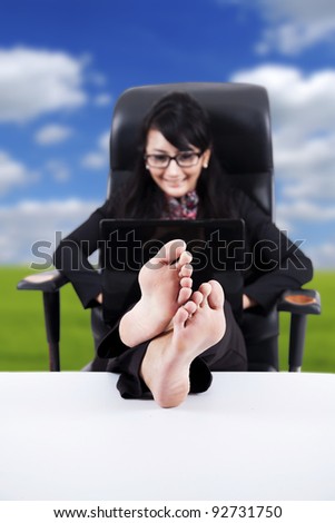 Businesswoman using laptop with Feet Up on a Table  isolated on white