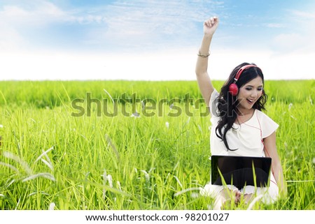 Asian woman enjoying summer by listens to digital music on her laptop outdoor