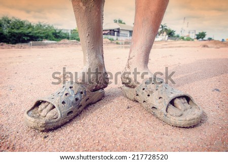 man wearing dirty sandals after mired in the mud with filtered