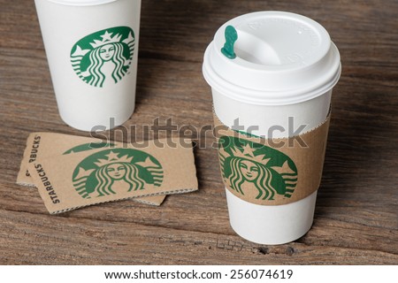 BANGKOK, THAILAND - FEBRUARY 26, 2015: White paper cup with sleeve with Starbucks logo. Starbucks is the world\'s largest coffee house with over 20,000 stores in 61 countries.